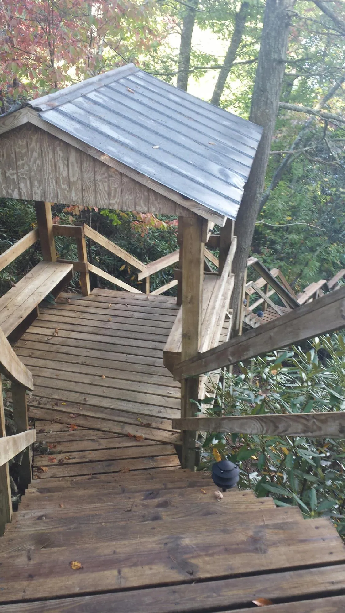 Metal roofed shelter over wooden steps on a wooded walkway — Skylight Repair & Installation work by our crew in Cresson