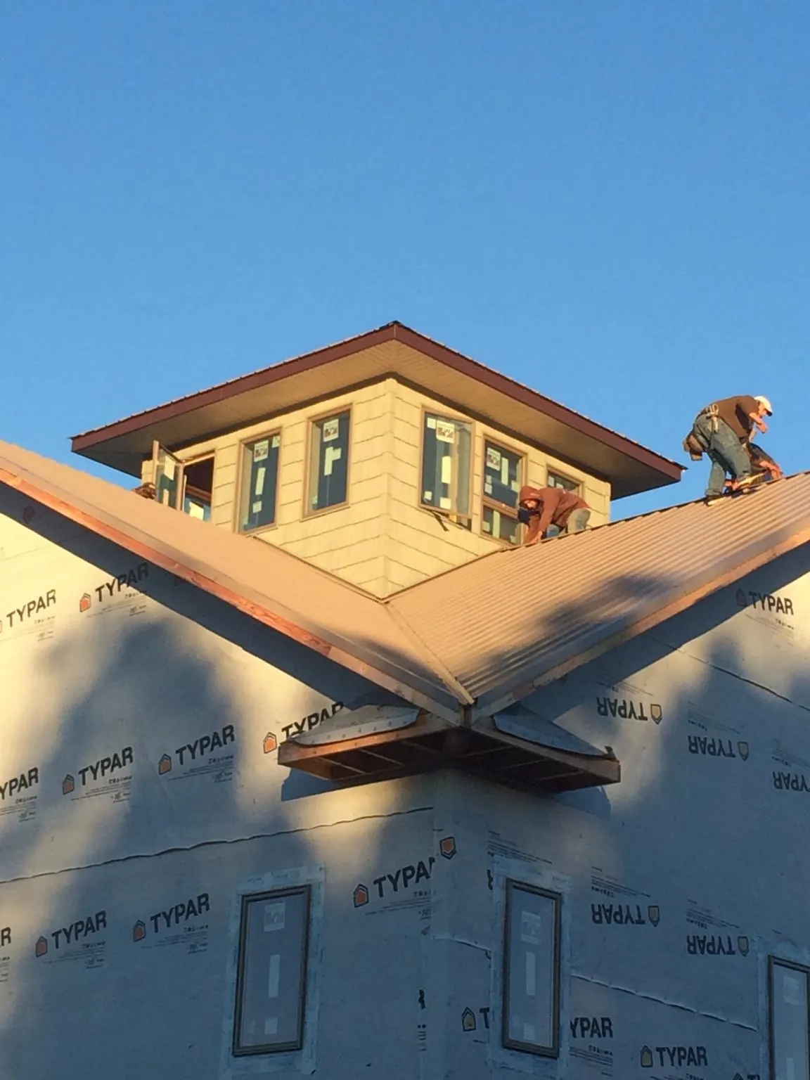 Roofers working around a rooftop cupola on a new metal roof at sunset — Roof Waterproofing in Cresson by Roofing Brothers